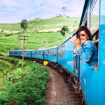 Happy Smiling Woman Looks Out From Window Traveling By Train On Most Picturesque Train Road In Sri Lanka Happy Smiling Woman Looks Out From Window Traveling By Train On Most Picturesque Train Road In Sri Lanka